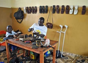 Umaru Kargbo, som blev förlamad i benen 10-åring, kan tack vare sin yrkesutbildning nu försörja både sig själv och sin familj. Här i sin verkstad tillsammans med sonen Mohammed.